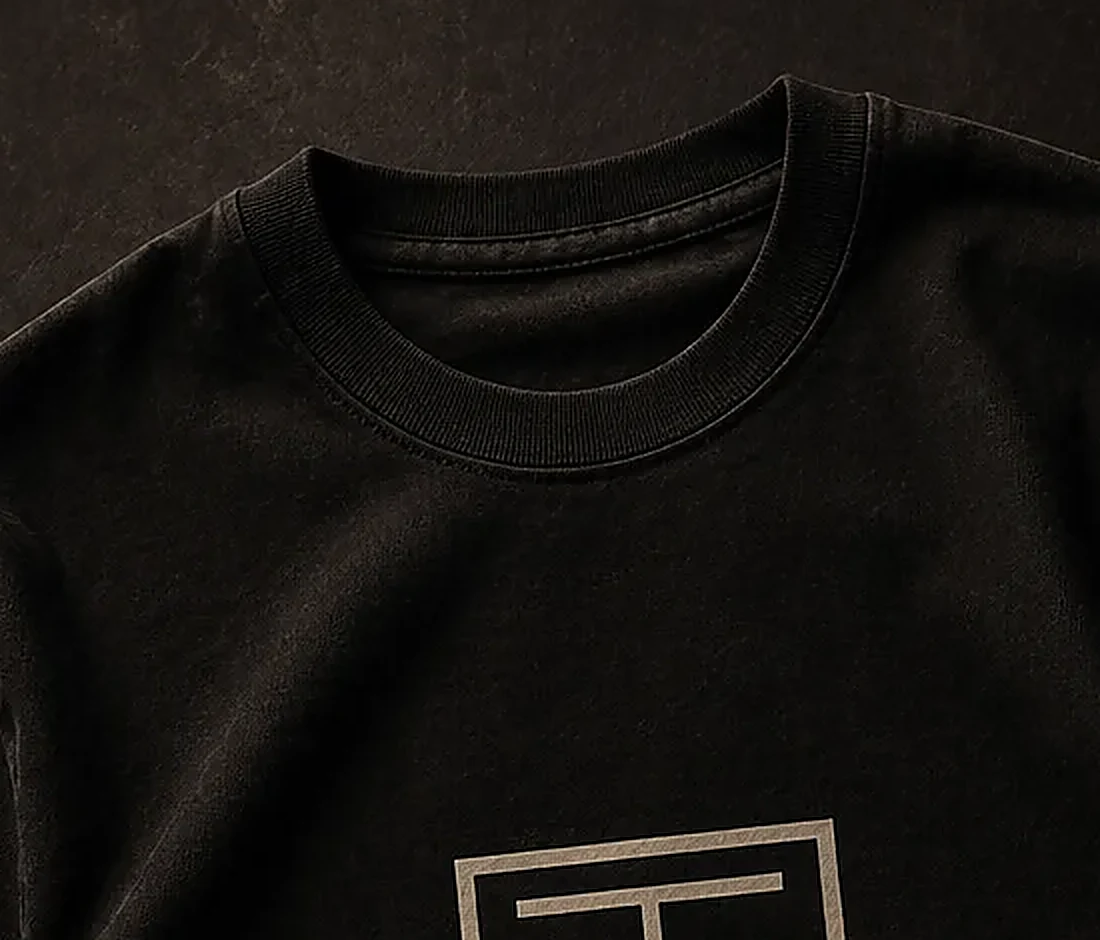 Archive Line Tee collar and upper chest showing the dense black jersey texture.