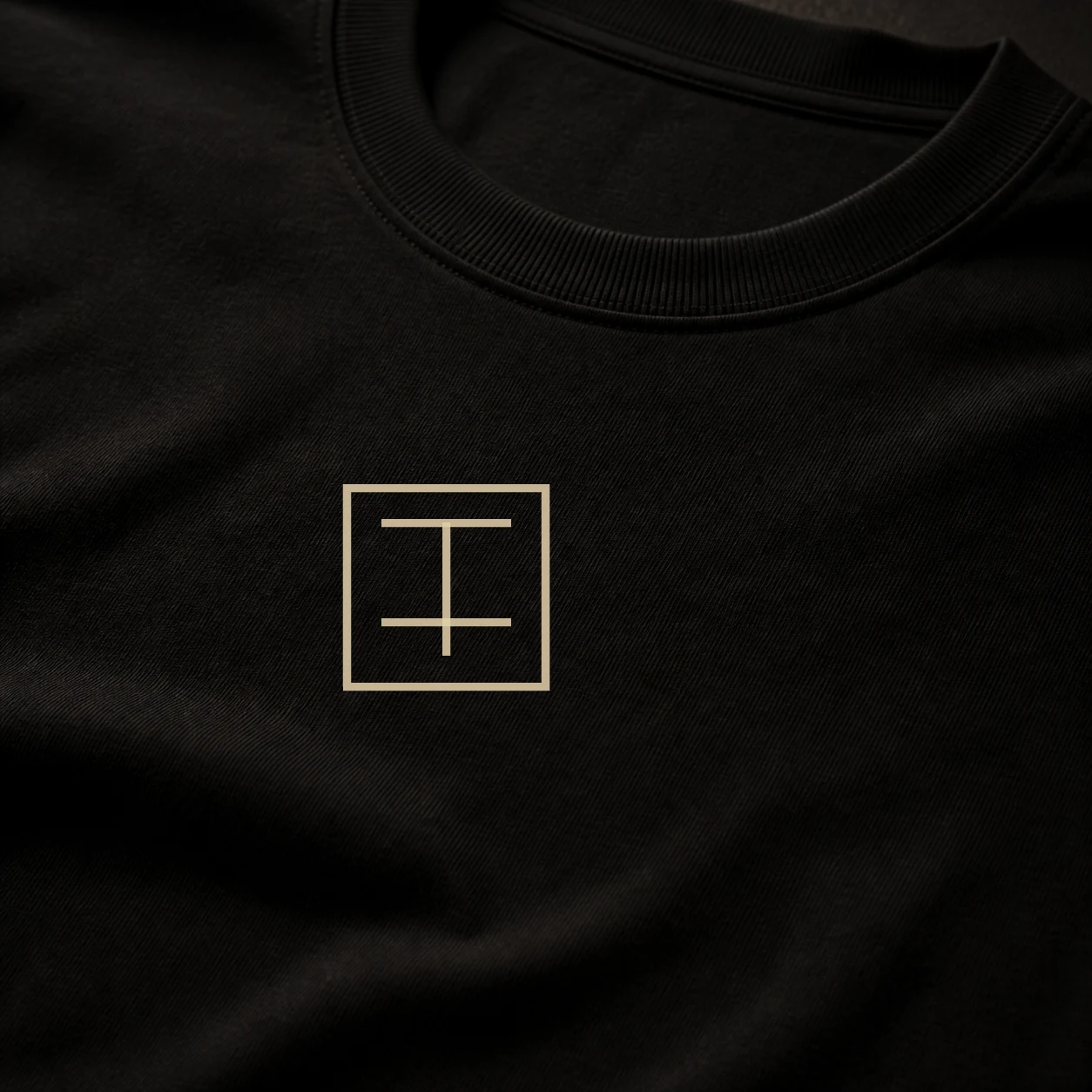 Close view of the Archive Line Tee chest mark printed over dense black cotton jersey.