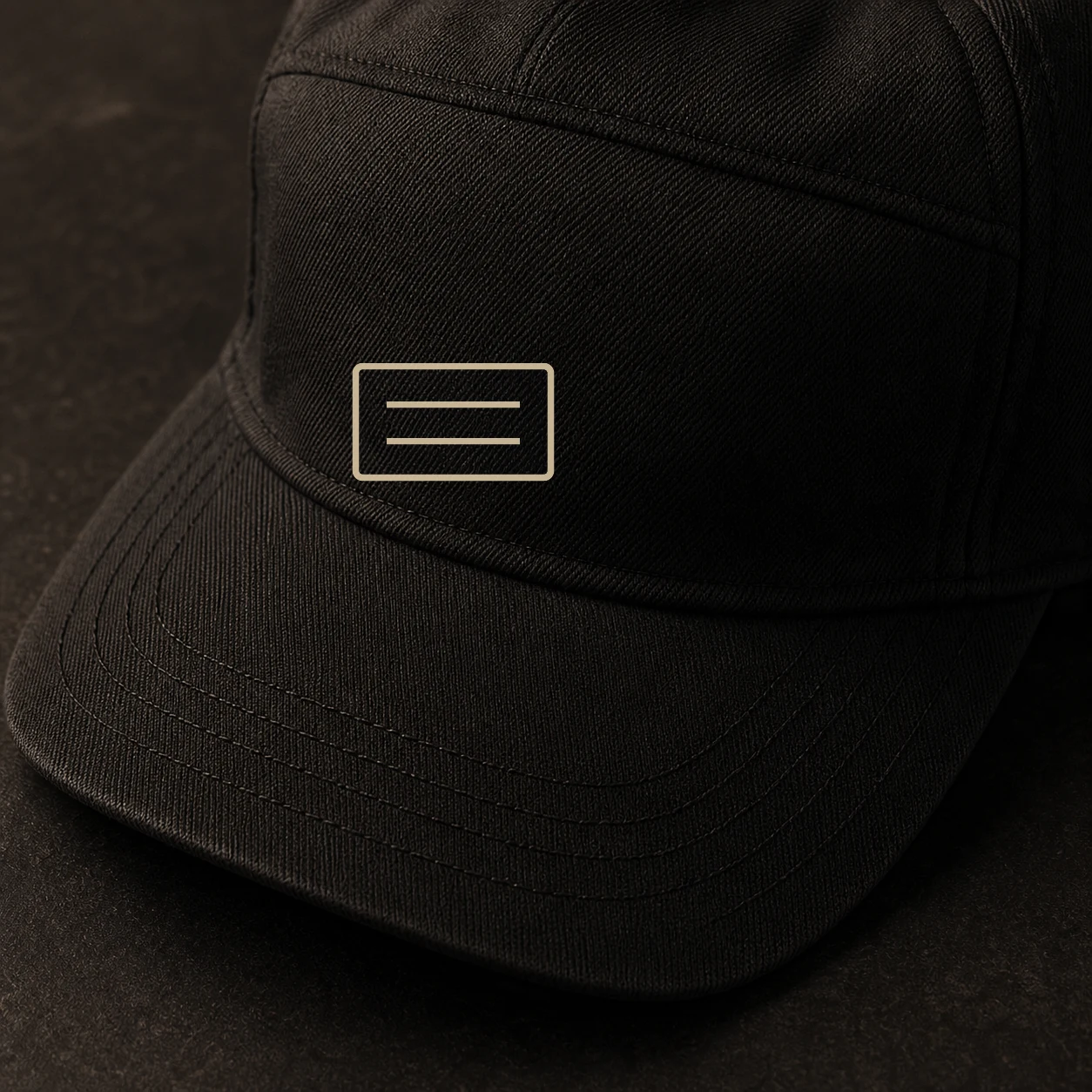 Close view of the Cityline Field Cap front-panel badge and brim stitching on black twill.
